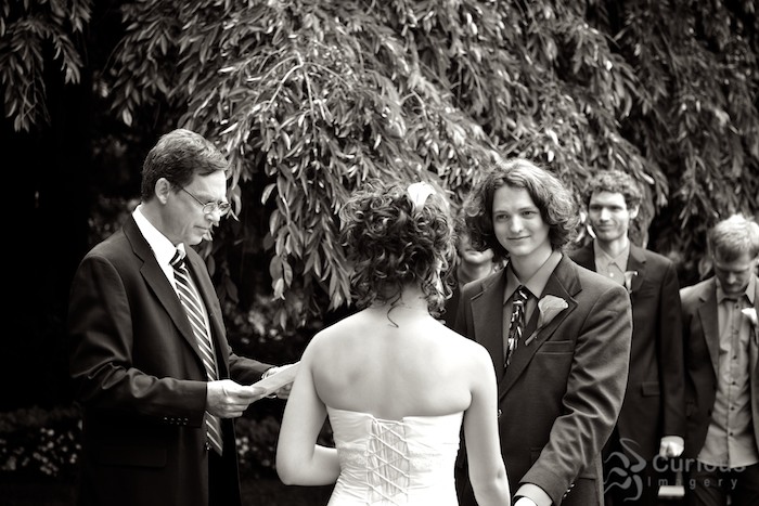 groom looking at bride during wedding ceremony in garden. black and white