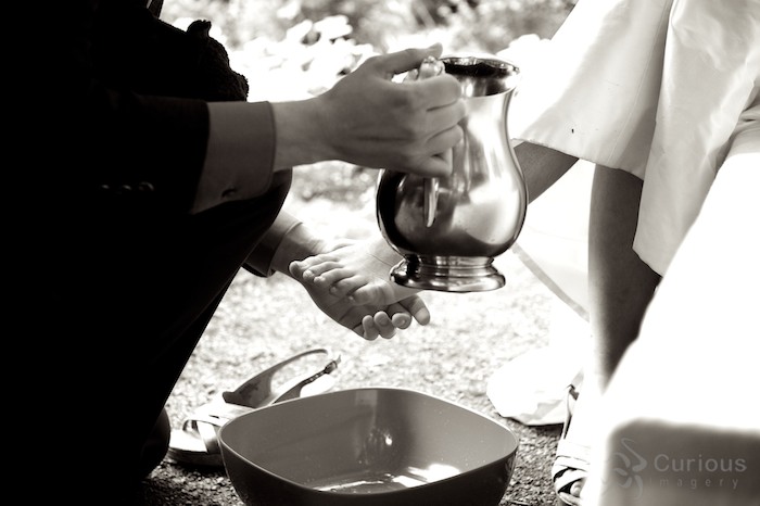 groom washing bride's feet. sepia tone black and white