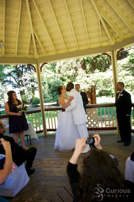 bride and groom kiss while audience takes pictures