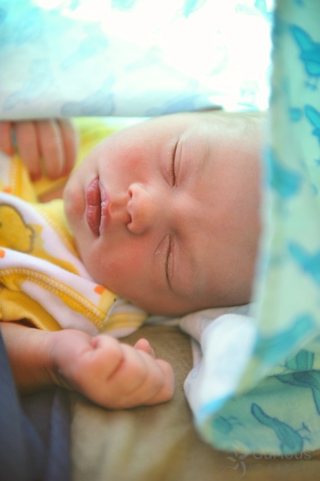 peaceful newborn baby boy bundled in blue cloth cocoon