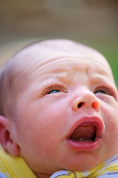 upset newborn baby furrowing brow and crying